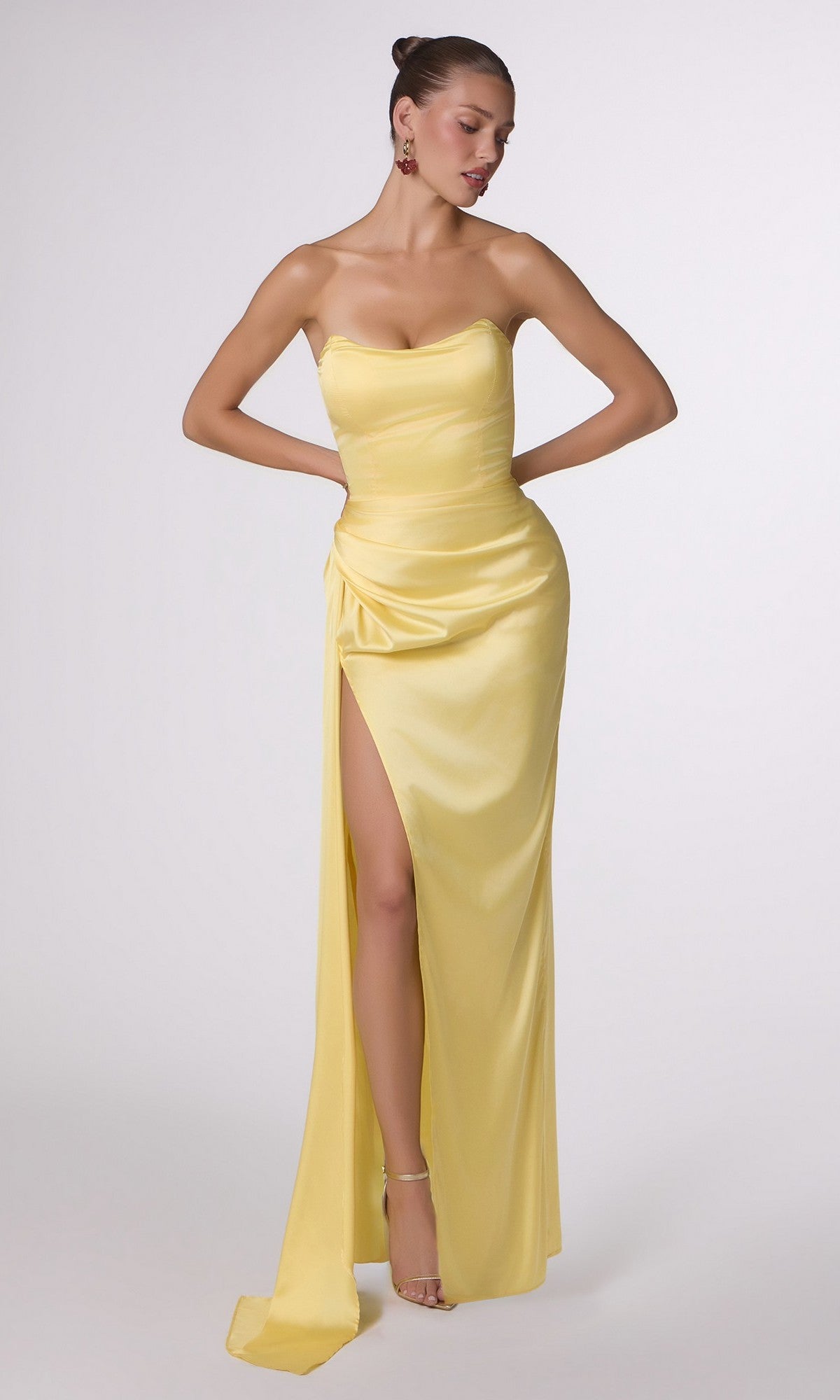 A woman wears the Strapless Long Satin Prom Dress CLT215 in light yellow, featuring a thigh-high slit, while standing against a plain white background.
